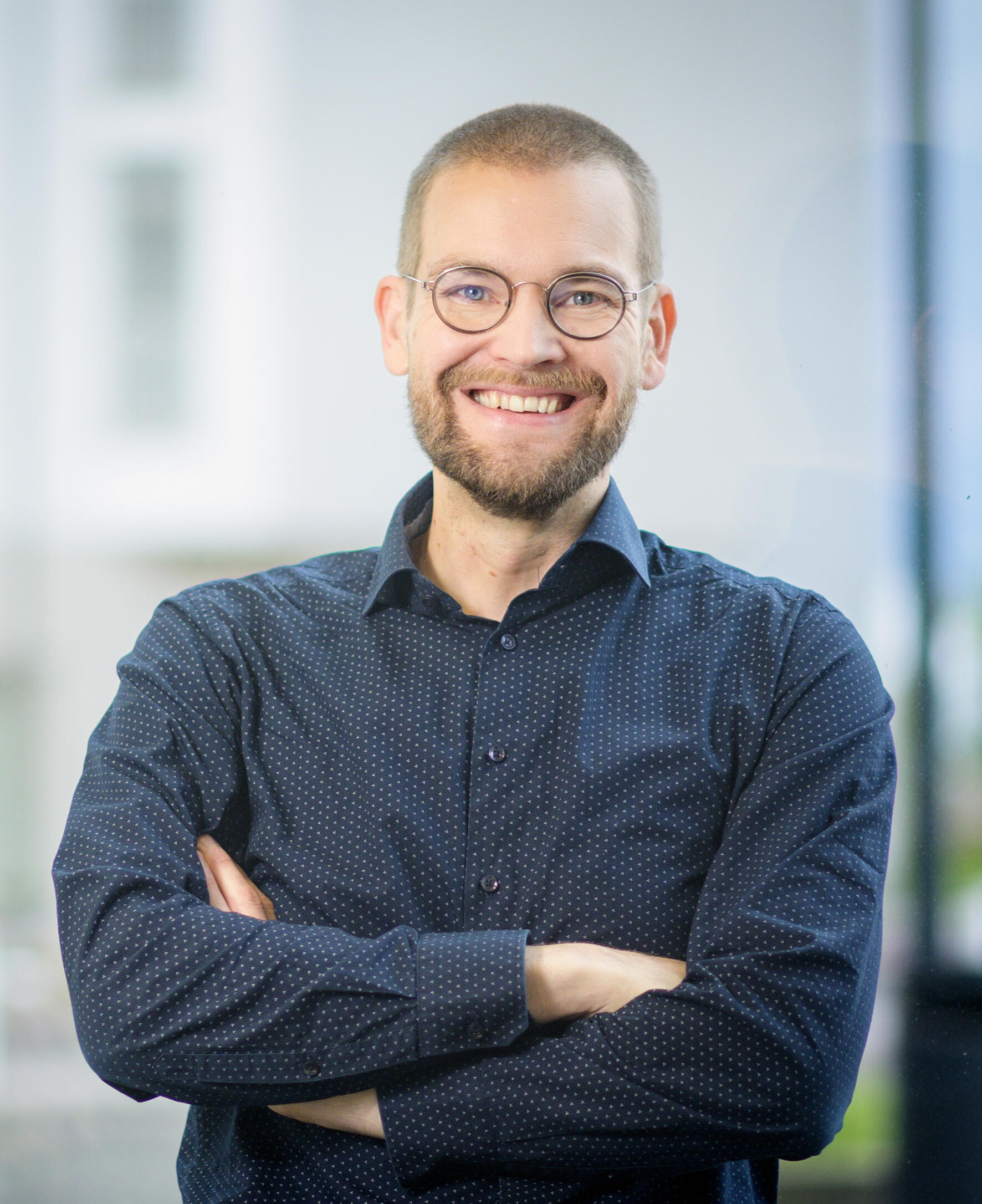 Eetu Niemi – Enterprise Architect, Consultant & Author Portrait of Eetu Niemi, enterprise architecture consultant and author, wearing a dark blue shirt and smiling confidently at the camera.
